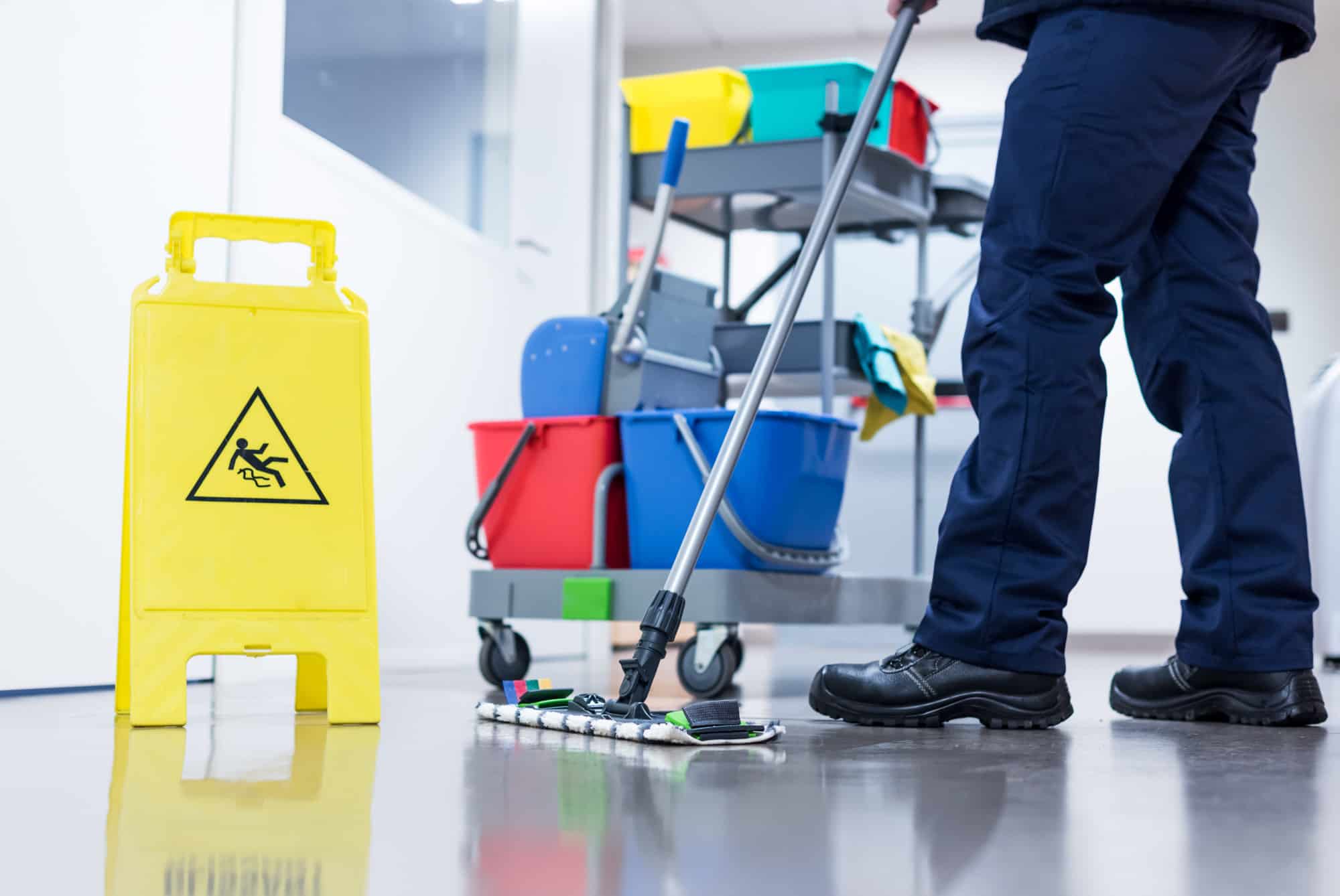 person mopping floor with wet floor sign